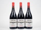 trois bouteilles de vin rouge posées l'une à côté de l'autre sur une surface blanche