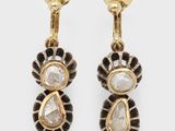 une paire de boucles d'oreilles dorées ornées de pierres blanches et noires