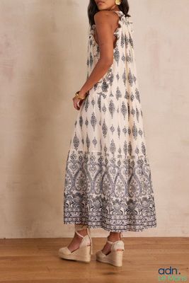 une femme vêtue d'une robe blanche et bleue, debout sur un plancher en bois