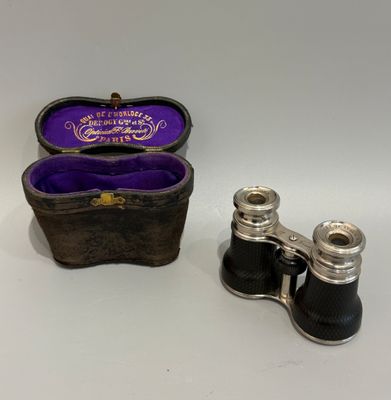 une paire de jumelles anciennes en métal argenté, avec un étui en velours violet