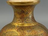 a gold vase sitting on a table with a gray background
