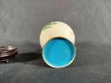 a small cup with a lid sitting next to a coin