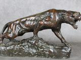statue en bronze représentant un lion sur un rocher, la gueule ouverte