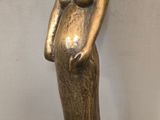 statue d'une femme en robe longue, debout, les mains sur les hanches