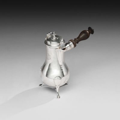 une cafetière en argent avec une poignée en bois posée sur une table