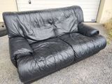 a black leather couch sitting in front of a garage door