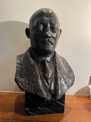 a bust of a man sitting on a table next to a lamp