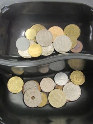 un bol noir contenant des pièces de monnaie, avec une cuillère à l'intérieur