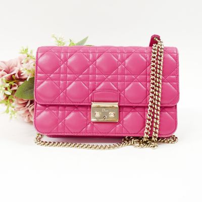 pink quilted purse with chain and flower on white background