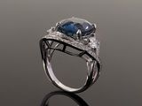an oval blue sapphire and diamond ring on a reflective surface