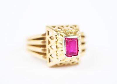 a close up of a gold ring with a pink stone