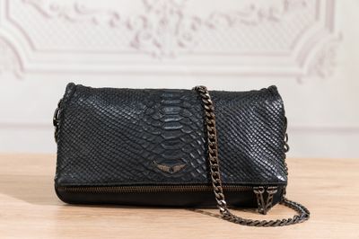 the black snake skin clutch bag is on a wooden table