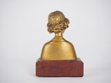 a gold statue of a woman with a red marble base
