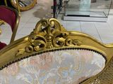 a gold chair in a room with a bike in the background