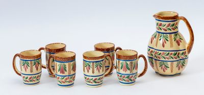 cinq tasses et un pichet posés les uns à côté des autres sur une table