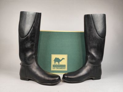 une paire de bottes en cuir noir avec une boîte verte en arrière-plan