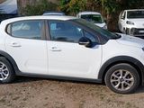a small white car parked in a lot with other cars