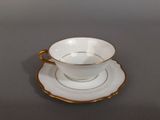 a white and gold cup and saucer sitting on a table