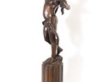 bronze statue of a boy holding a bird on a pedestal