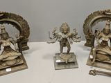 trois figurines en bronze représentant des divinités hindoues, posées sur des socles sur une table