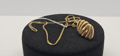 un gros plan sur une boîte noire sur laquelle est posé un collier en or