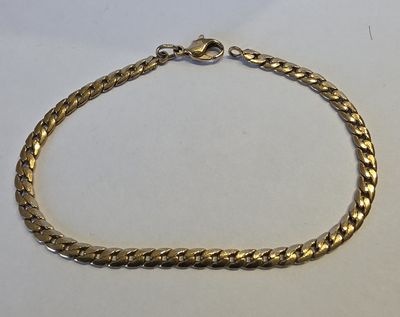 gros plan d'un bracelet en chaîne en or sur une surface blanche