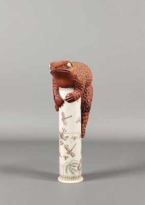 une figurine représentant une grenouille assise au sommet d'un pilier