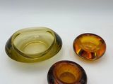 three different colored glass objects on a white surface