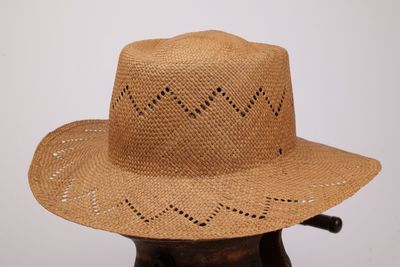 un chapeau de paille troué posé sur un support en bois