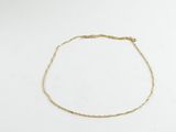 gros plan d'un bracelet en chaîne en or sur une surface blanche