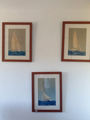 trois tableaux accrochés au mur au-dessus d'un lit