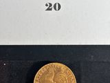 a gold coin in a black box with a white label