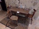a table and chairs in a room with a stone wall in the background