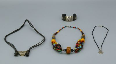 Trois colliers, un bracelet et un collier de perles sont posés sur une table