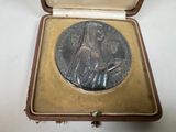 une petite médaille en argent dans un écrin posé sur une table