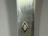 a close up of a silver spoon with a diamond on it
