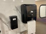 a black paper towel dispenser on the wall in a public restroom