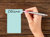woman ' s hand holding a pen and writing on a notepad with the word celine written on it