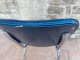 a black chair with a blue seat on a brick floor