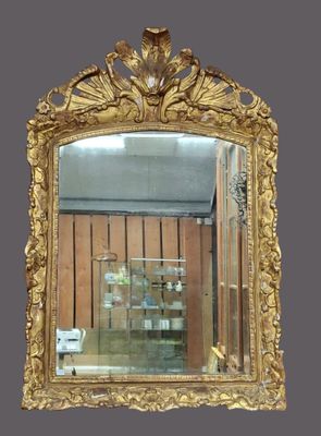 un miroir à cadre doré accroché au mur de la pièce