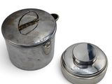 a silver pot and a silver lid on a white surface