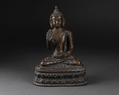 a bronze figure of a seated buddha on a pedestal