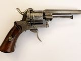 un vieux revolver avec une poignée en bois sur une surface blanche