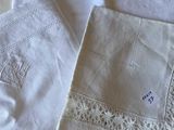 three white linen napkins with embroidered designs on them sitting on a table