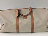 une photo d'un sac de voyage beige et marron posé sur une table