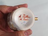 a person holding a small white vase with writing on it