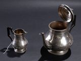 a silver tea pot and a silver teapot on a table