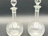pair of clear glass decanters sitting on top of a table