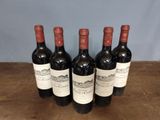 six bottles of wine are lined up on a wooden table