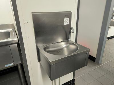 un lavabo en acier inoxydable au milieu de toilettes publiques